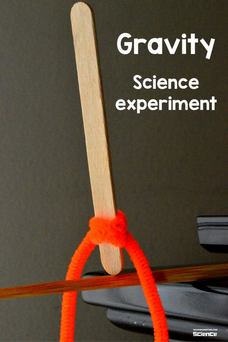 Craft stick with orange pipecleaner wrapped around it is balancing on a chopstick. It's a Center of Gravity Science Kids Activities - Science Experiments For Kids - STEM
