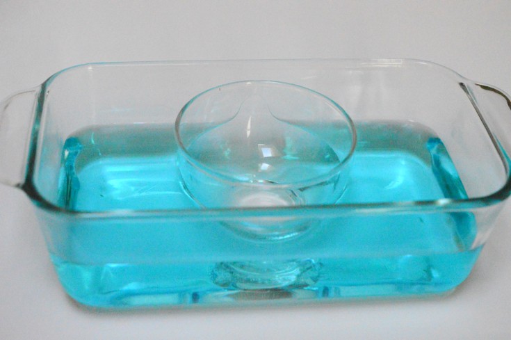 small container placed inside big container with blue water