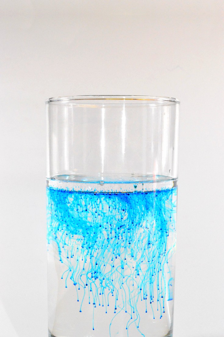 blue particles sinks in a glass of water through diffusion