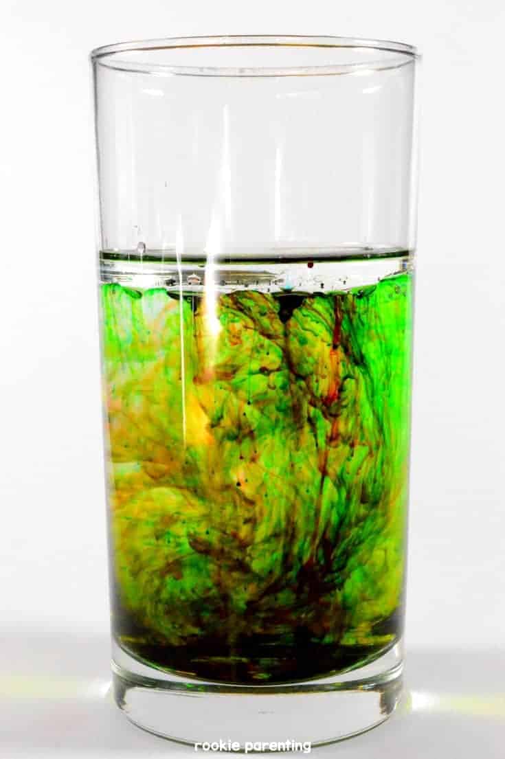 a glass of water with different color mixing together in traces