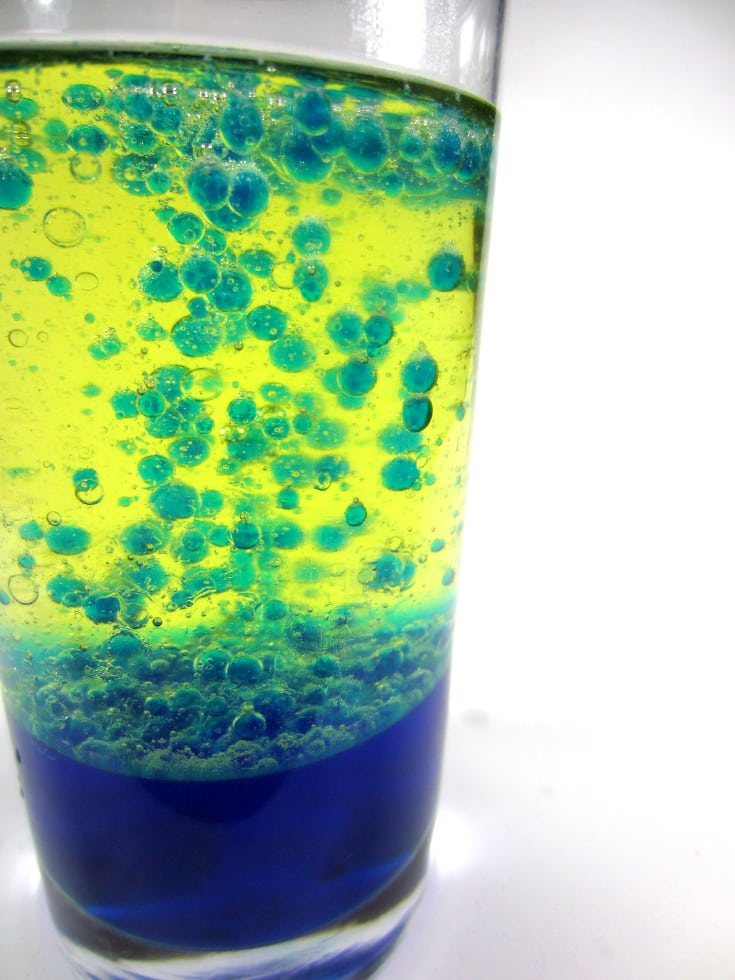 Blue water and yellow vegetable oil with blue bubbles rising. It is a lava lamp using vegetable oil.