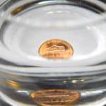 penny at bottom of glass with water shows a reflection