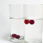 two grapes sink in one glass of water, another two grapes float in a glass of water