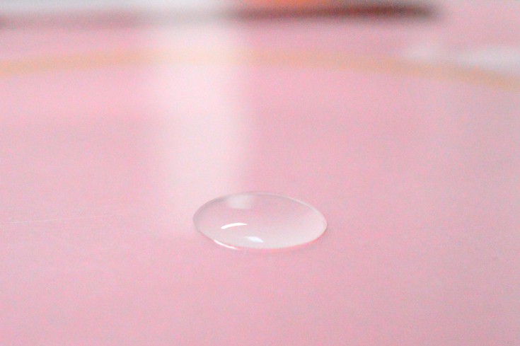 A drop of water on a pink surface, try this surface tension science project.
